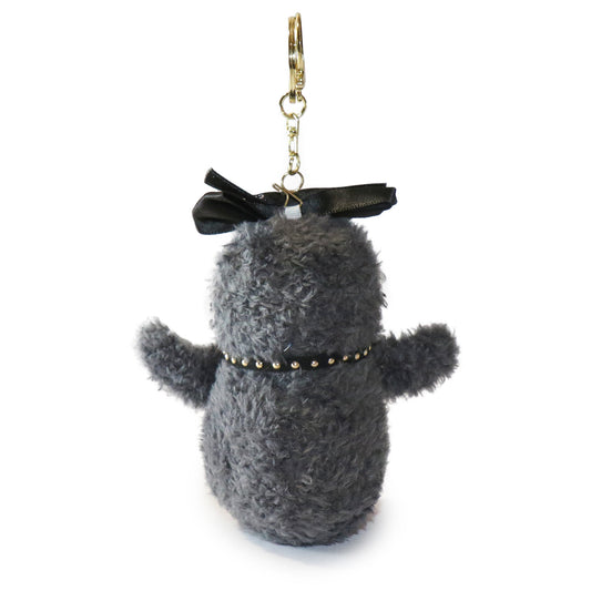 The backside of Fritter Penguin keychain with a black bow, and gold accents on a white background