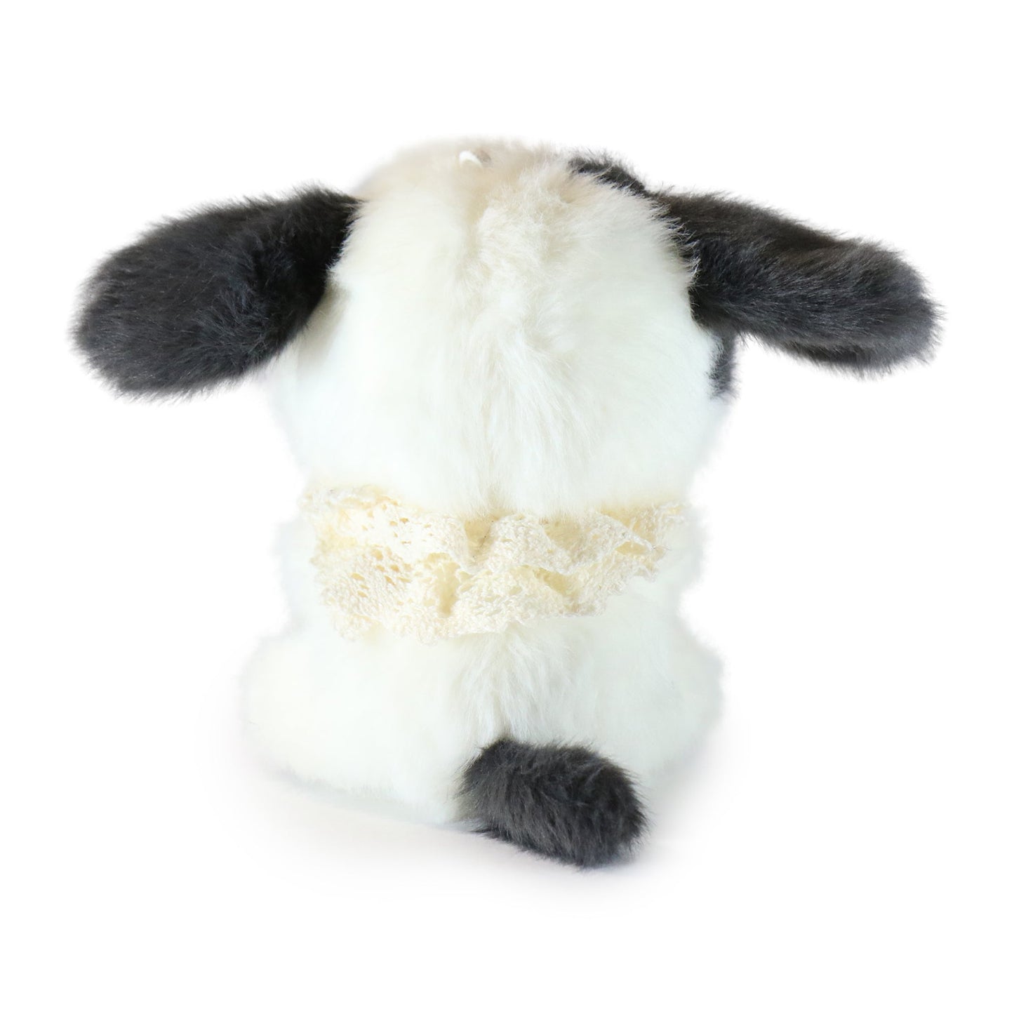 Backside of white and black plush toy dog on a white background.