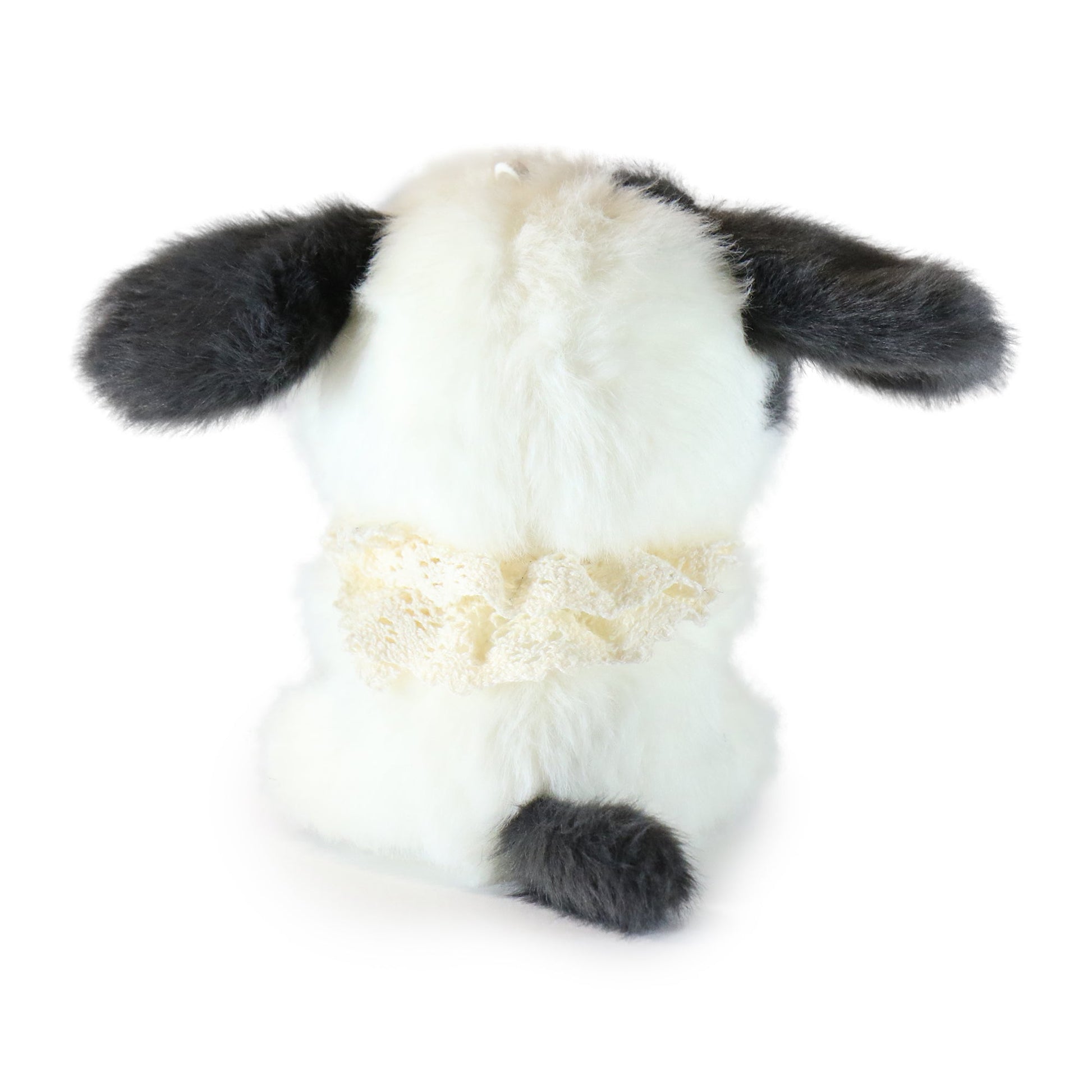 Backside of white and black plush toy dog on a white background.