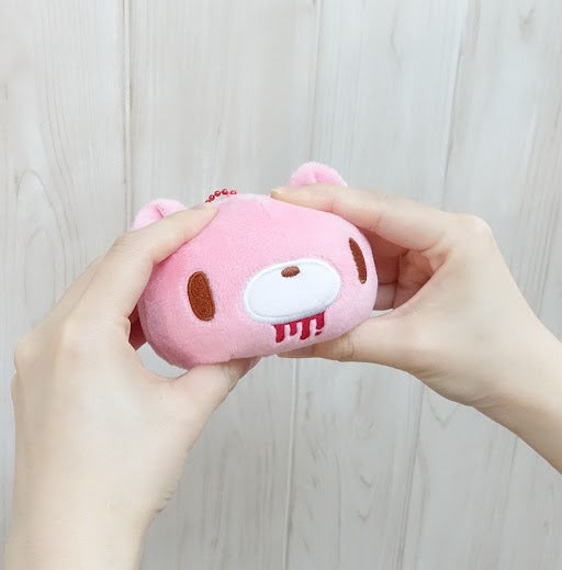 Pink plush toy held by hands against a light wooden background